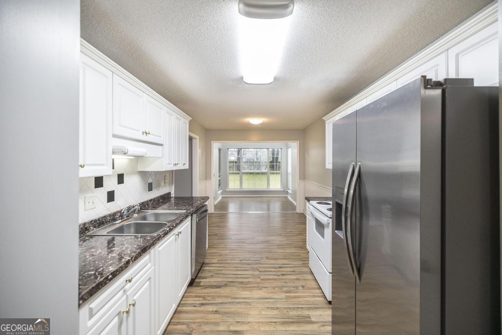 319 Smithville Church Road Warner Robins, GA 31088 - Photo 15 of 34 a kitchen with stainless steel appliances granite countertop a refrigerator a sink dishwasher a stove and a dining table with wooden floor