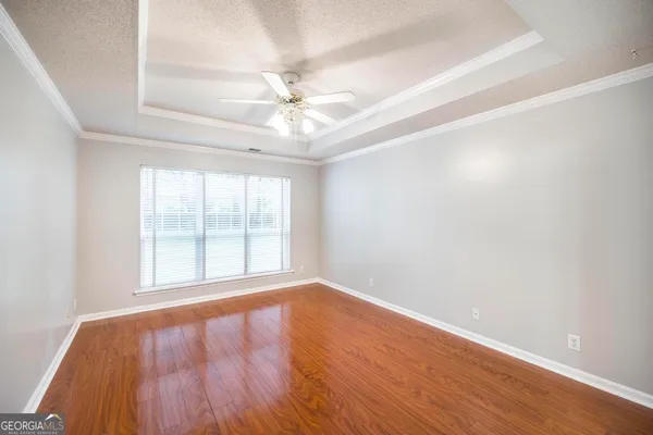 an empty room with wooden floor fan and windows