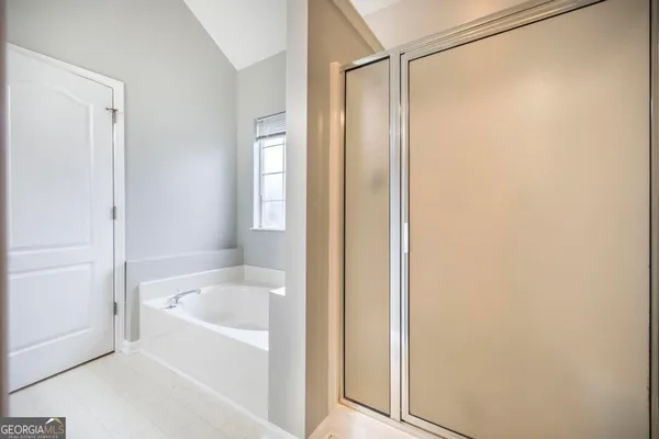 a white bath tub with shower and a sink