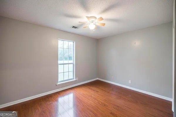 an empty room with wooden floor and windows