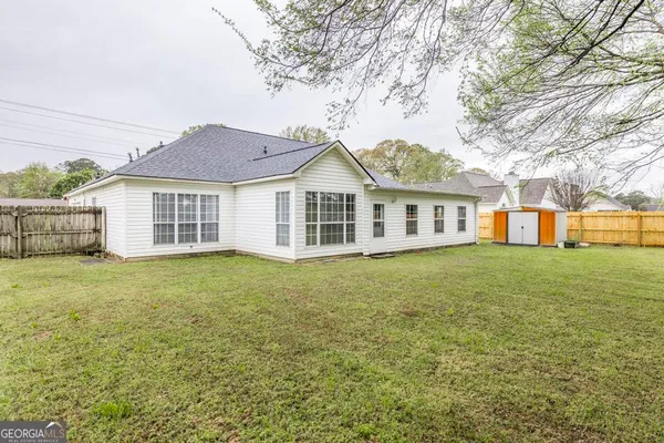 a view of a house with a garden and tall tree
