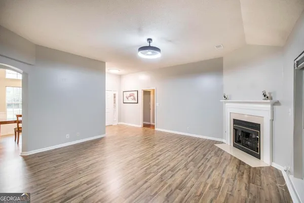 an empty room with wooden floor fireplace and windows