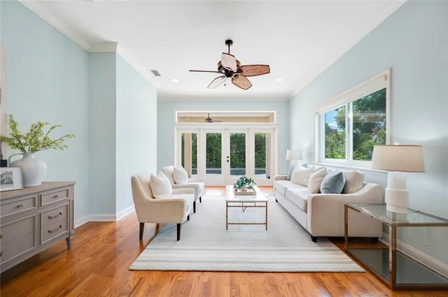 a living room with couches a coffee table and a chandelier with wooden floor