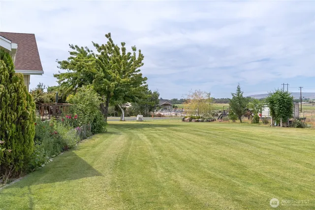 a view of a big yard of grass and basketball court