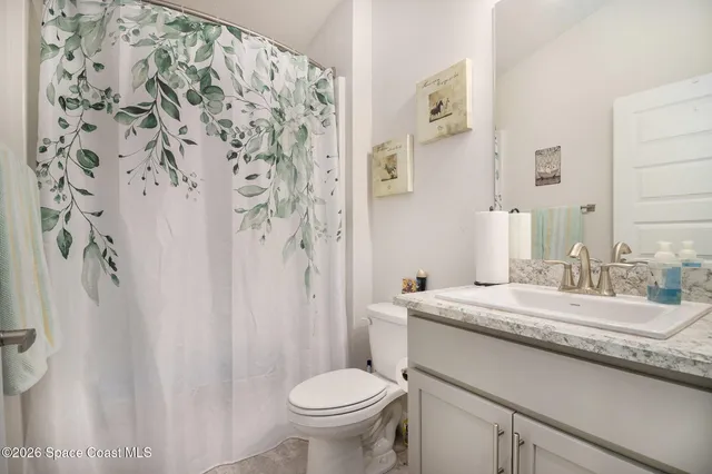 a bathroom with a granite countertop sink toilet and a mirror