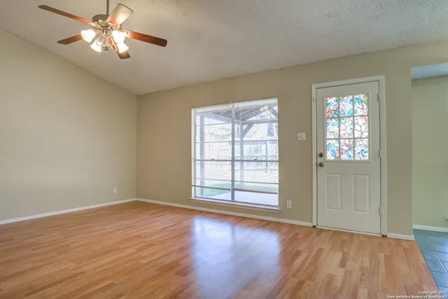 a view of empty room with wooden floor and fan