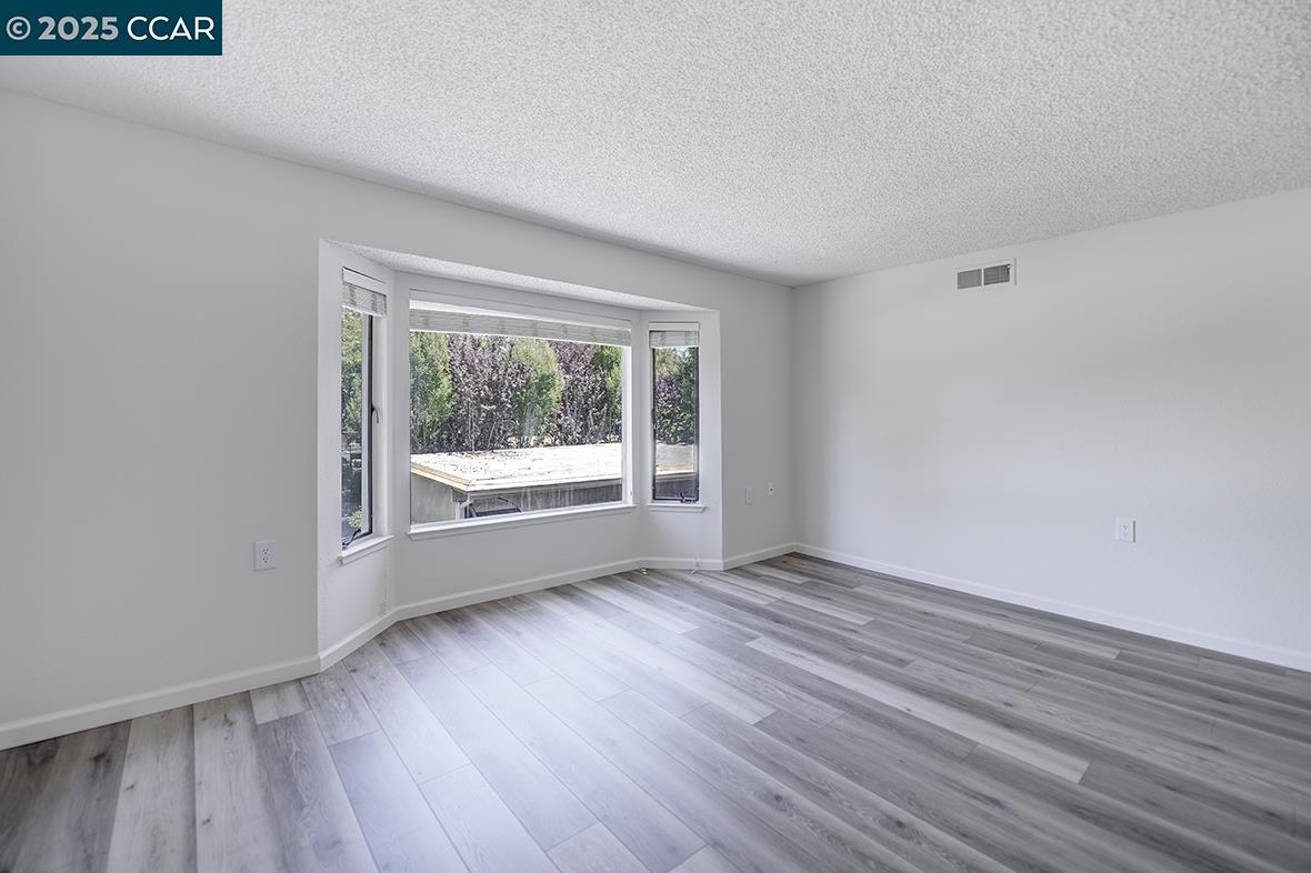 1333 Singingwood Court, Unit 1 Walnut Creek, CA 94595 - Photo 11 of 34 a view of an empty room with wooden floor and a window