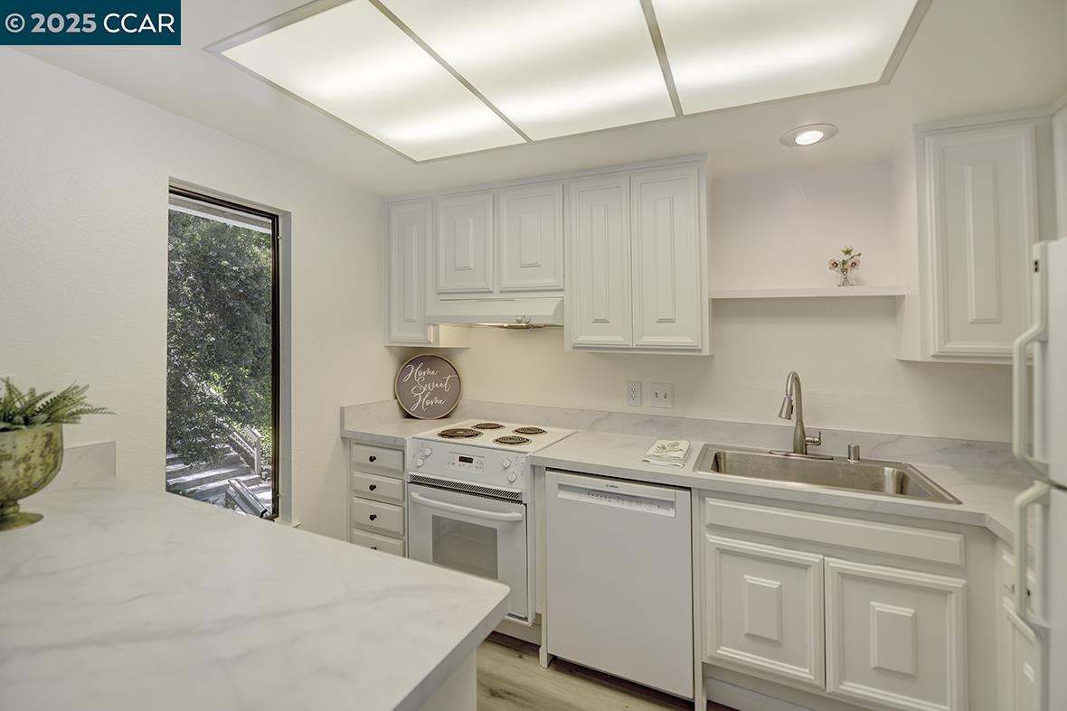 1333 Singingwood Court, Unit 1 Walnut Creek, CA 94595 - Photo 7 of 34 a kitchen with stainless steel appliances white cabinets and a sink