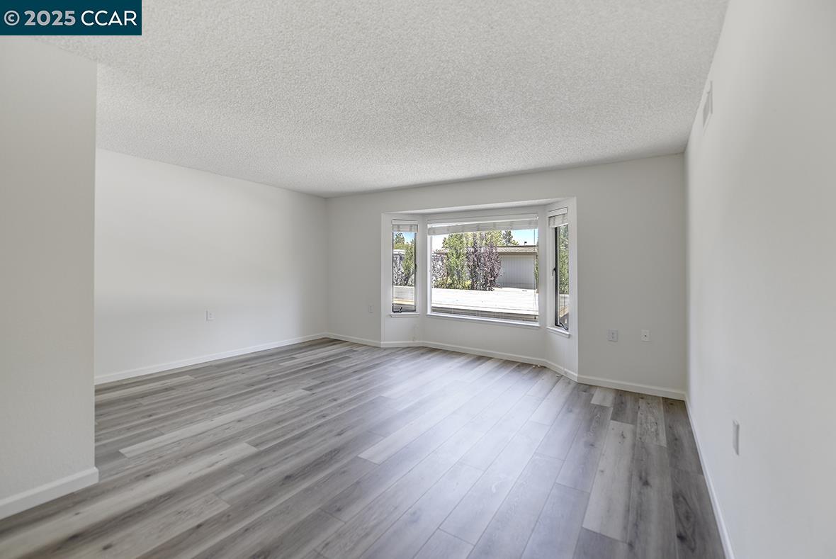 1333 Singingwood Court, Unit 1 Walnut Creek, CA 94595 - Photo 10 of 34 an empty room with wooden floor and windows