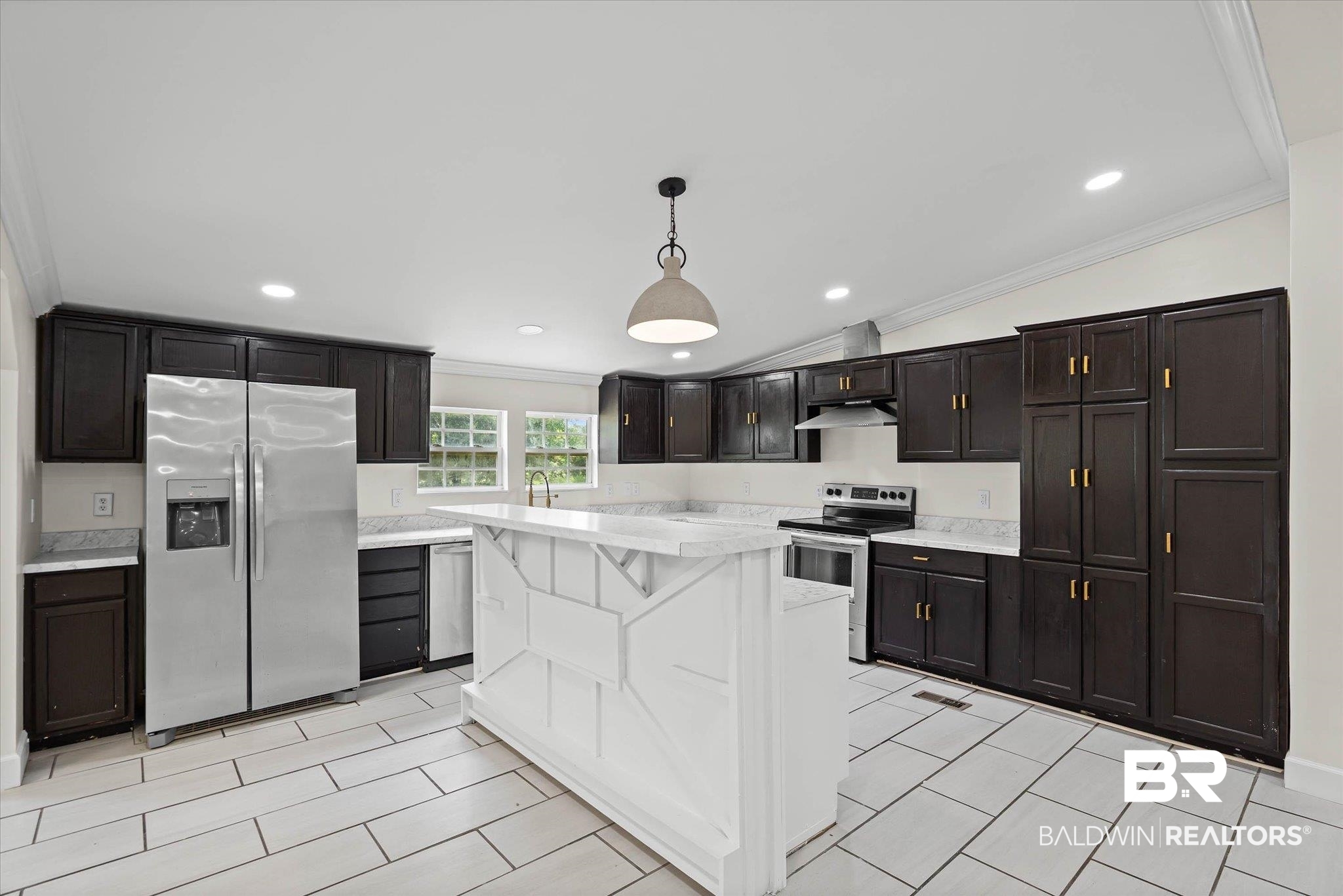 9230 McLeod Road Mobile, AL 36695 - Photo 8 of 20 Kitchen featuring a central island with a bar-height counter, dark wood cabinetry with gold-tone hardware, light-toned tile flooring, stainless steel appliances, and recessed lighting