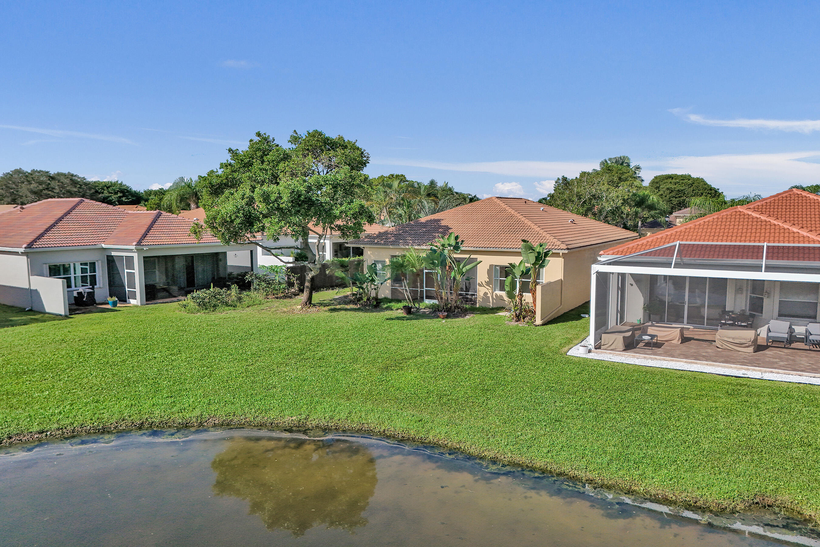 15874 Vivanco Street Delray Beach, FL 33446 - Photo 26 of 33 a backyard of a house with table and chairs under an umbrella
