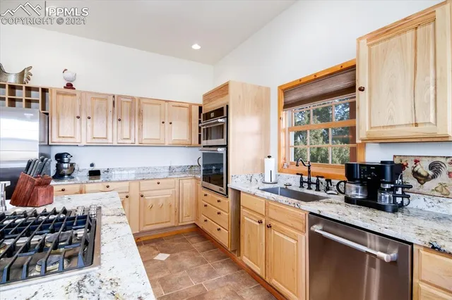 a kitchen with stainless steel appliances a stove a sink a kitchen island with chairs and white cabinets