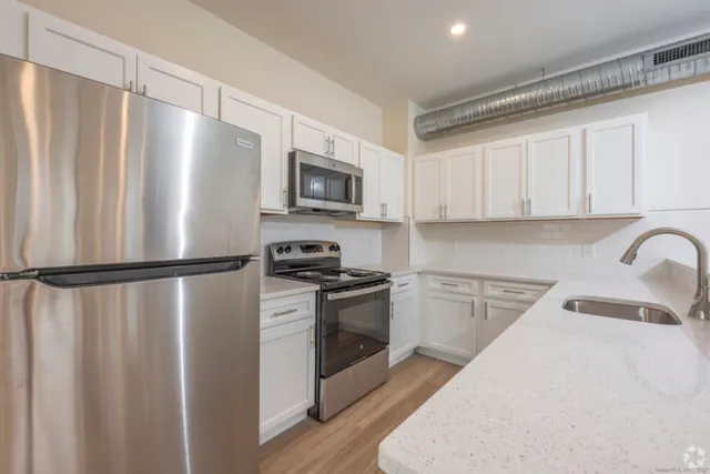 a kitchen with stainless steel appliances a refrigerator sink and white cabinets