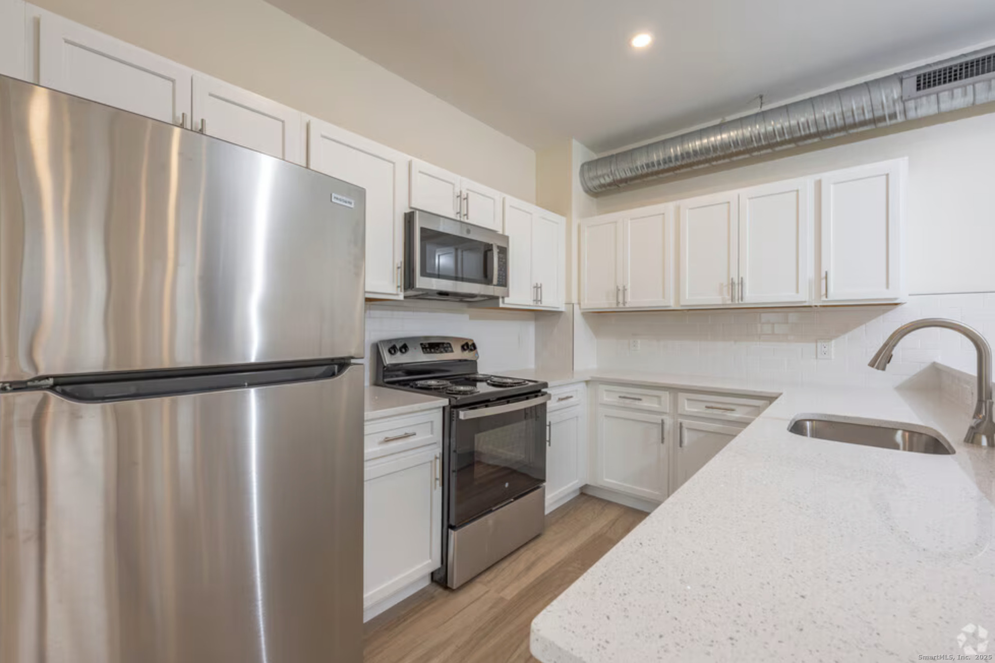a kitchen with stainless steel appliances a refrigerator sink and white cabinets