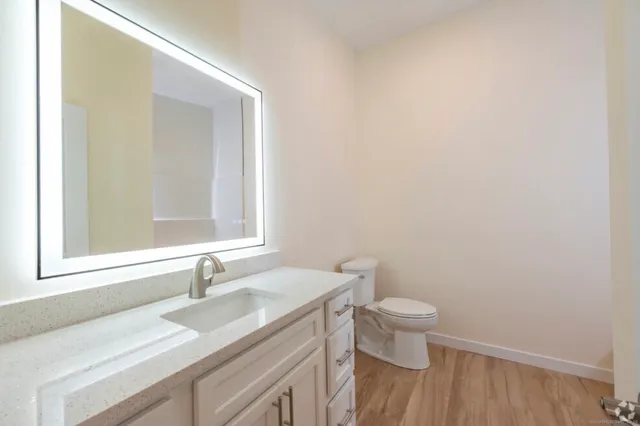 a bathroom with a granite countertop sink a toilet and a mirror