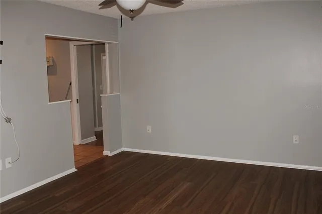 a view of an empty room with wooden floor and a ceiling fan