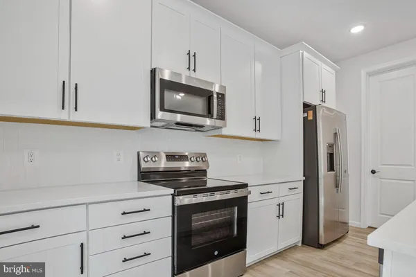a kitchen with stainless steel appliances white cabinets and a stove a refrigerator with wooden floor