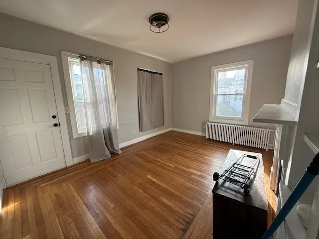 a view of an empty room with wooden floor and a window