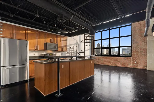 a kitchen with stainless steel appliances granite countertop a refrigerator a sink dishwasher a stove and a dining table with wooden floor