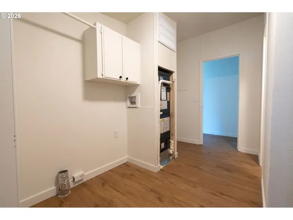 a view of an empty room with wooden floor and window