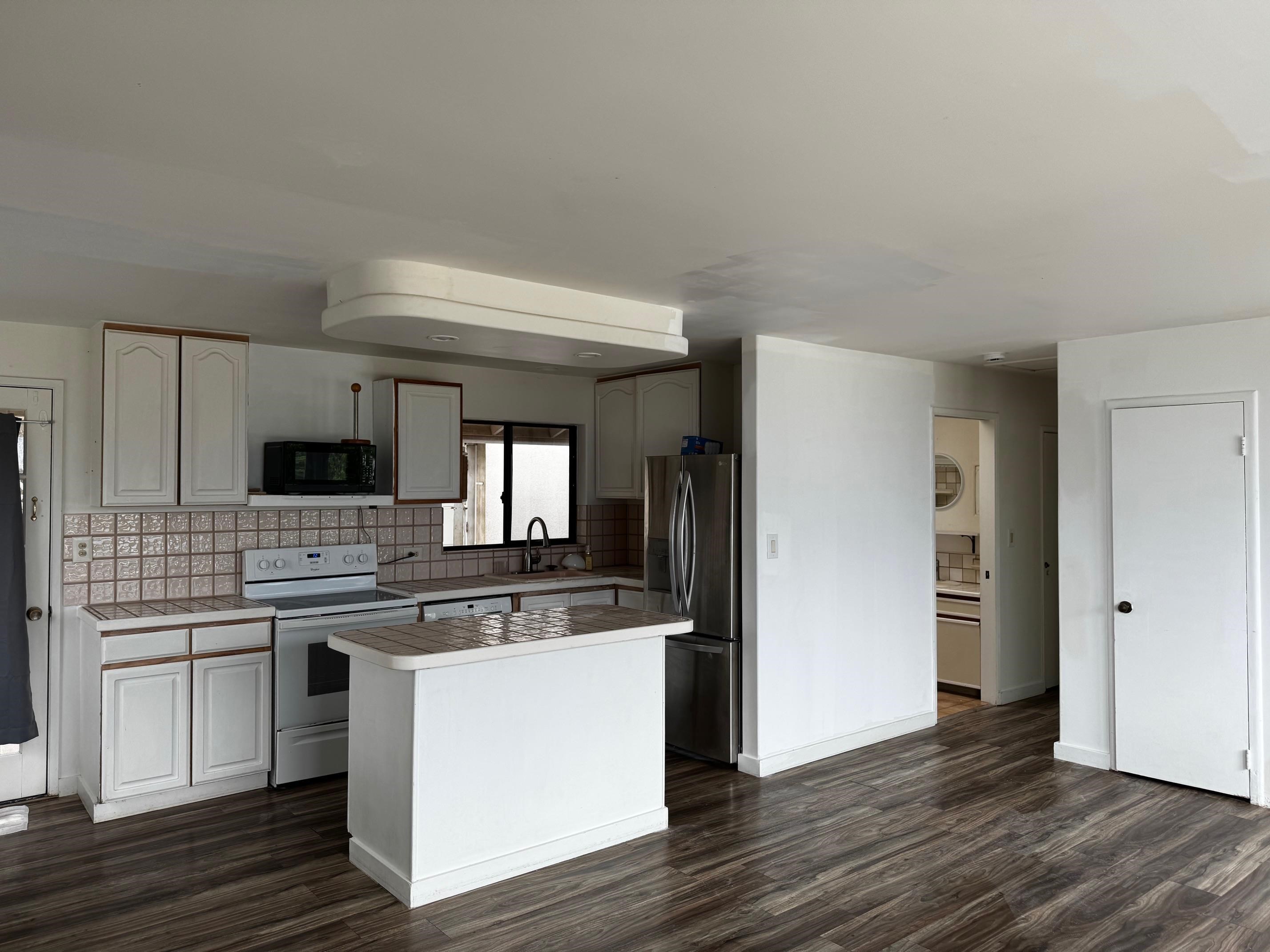 40 Kalihi Place Kula, HI 96790 - Photo 3 of 15 a kitchen with stainless steel appliances a stove top oven a refrigerator a sink and dishwasher with wooden floor