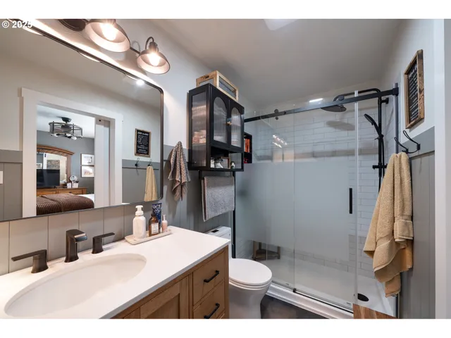 a bathroom with a sink a toilet a mirror and shower