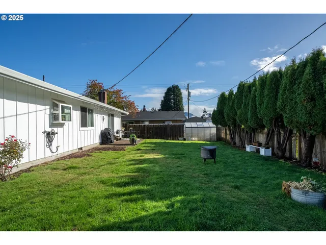 a backyard of a house with table and chairs plants and large tree