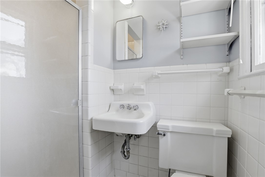 4304 Old Buncombe Road Greenville, SC 29617 - Photo 22 of 50 This clean and bright bathroom features classic white tile and a wall-mounted sink.