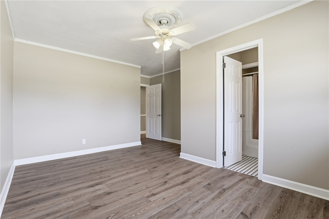 4304 Old Buncombe Road Greenville, SC 29617 - Photo 24 of 50 This spacious bedroom features wood flooring, a ceiling fan, and access to an adjoining bathroom.