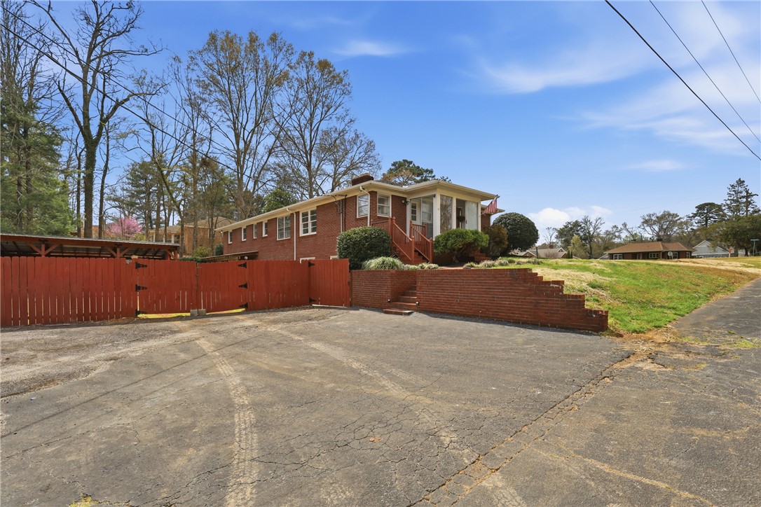 4304 Old Buncombe Road Greenville, SC 29617 - Photo 43 of 50 This classic brick residence presents a welcoming facade, complemented by mature trees and a vibrant red fence.