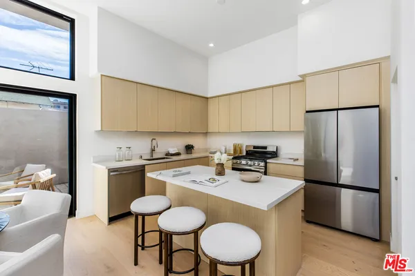 a kitchen with stainless steel appliances a refrigerator a sink a stove a table and chairs