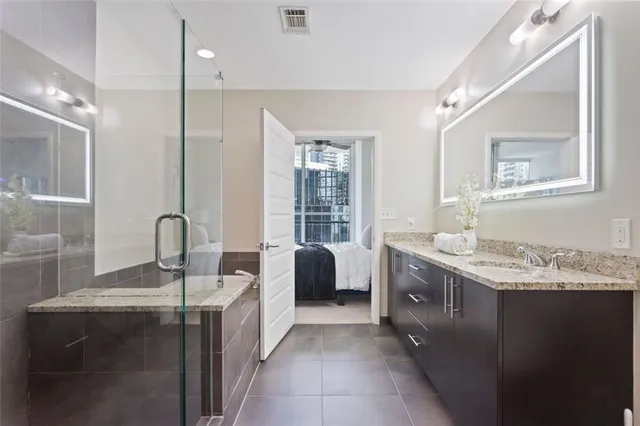 a spacious bathroom with a granite countertop sink a large mirror and a bathtub