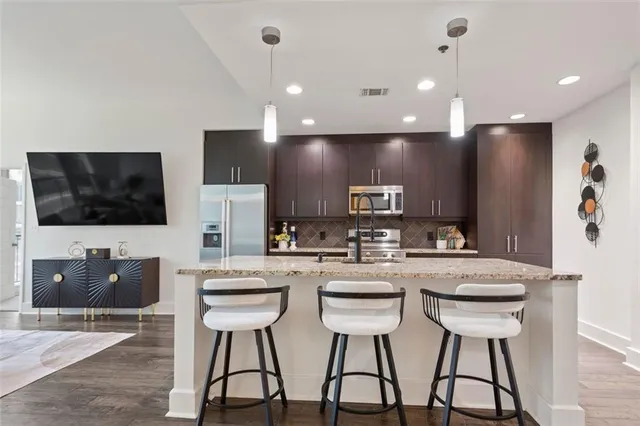 a kitchen with stainless steel appliances kitchen island granite countertop a refrigerator a stove a microwave oven with white cabinets and chairs