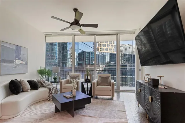 a living room with furniture a flat screen tv and a large window