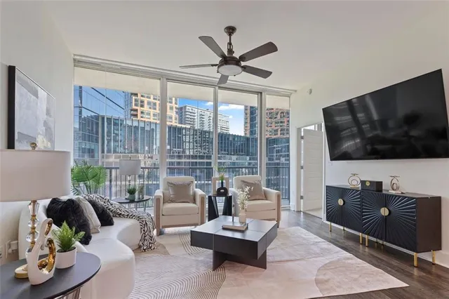 a living room with furniture floor to ceiling window hardwood floor and a flat screen tv