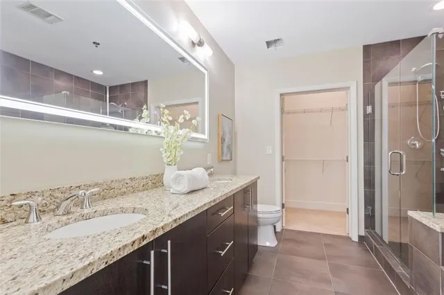 a bathroom with a granite countertop sink a mirror and a shower