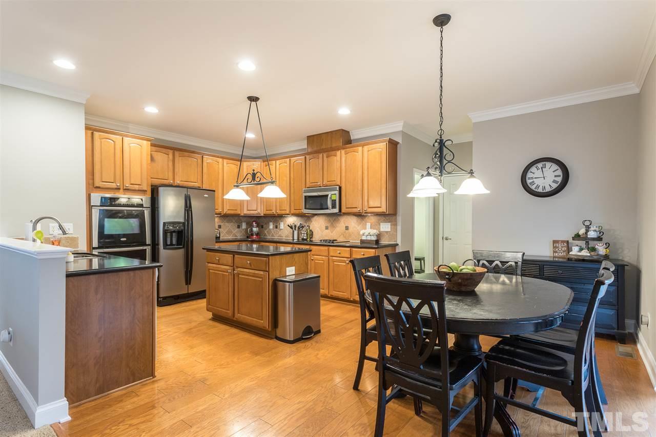107 Locke Woods Road Raleigh, NC 27603 - Photo 7 of 30 a kitchen with stainless steel appliances granite countertop a sink a stove a dining table chairs and chandelier