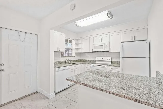a kitchen with granite countertop cabinets and refrigerator