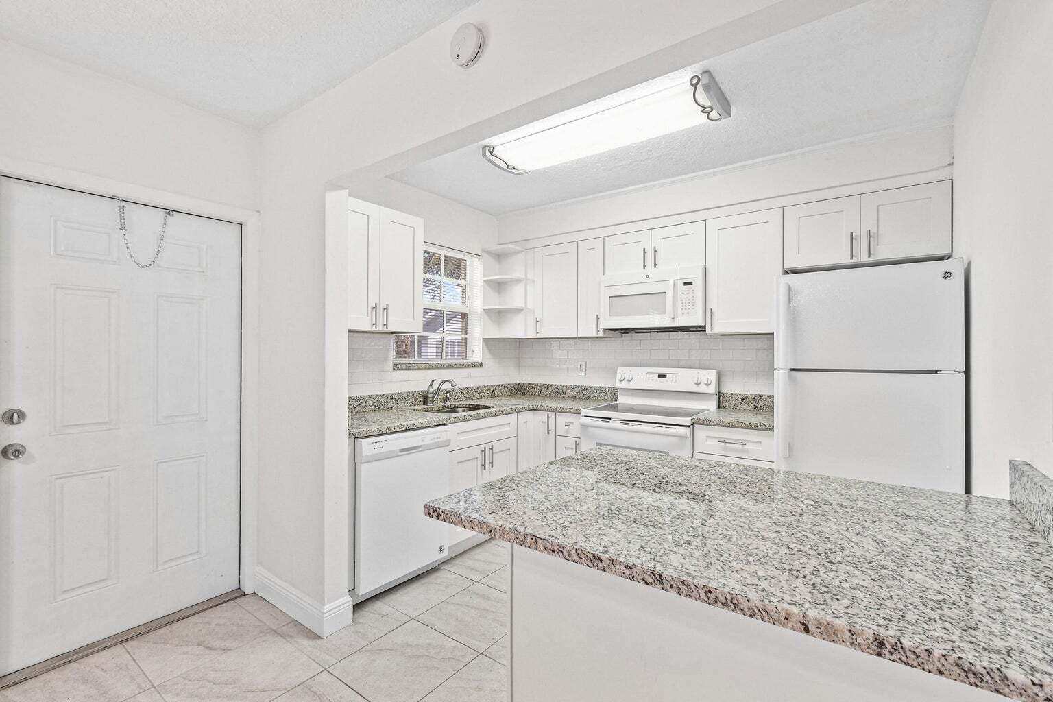 101 Akron Street, Unit 101 Lake Worth Beach, FL 33461 - Photo 2 of 11 a kitchen with granite countertop cabinets and refrigerator
