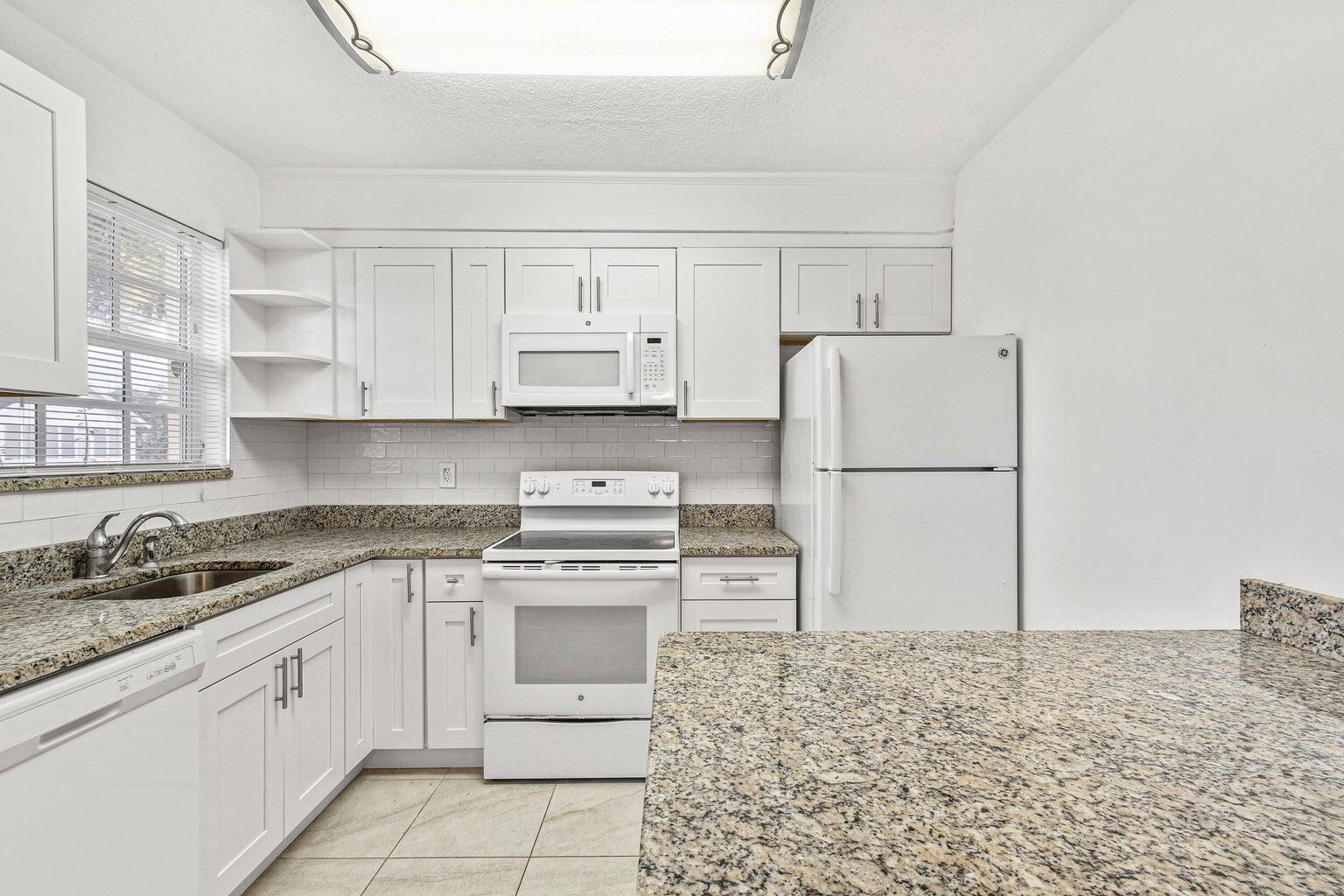 101 Akron Street, Unit 101 Lake Worth Beach, FL 33461 - Photo 4 of 11 a kitchen with cabinets appliances and a counter space