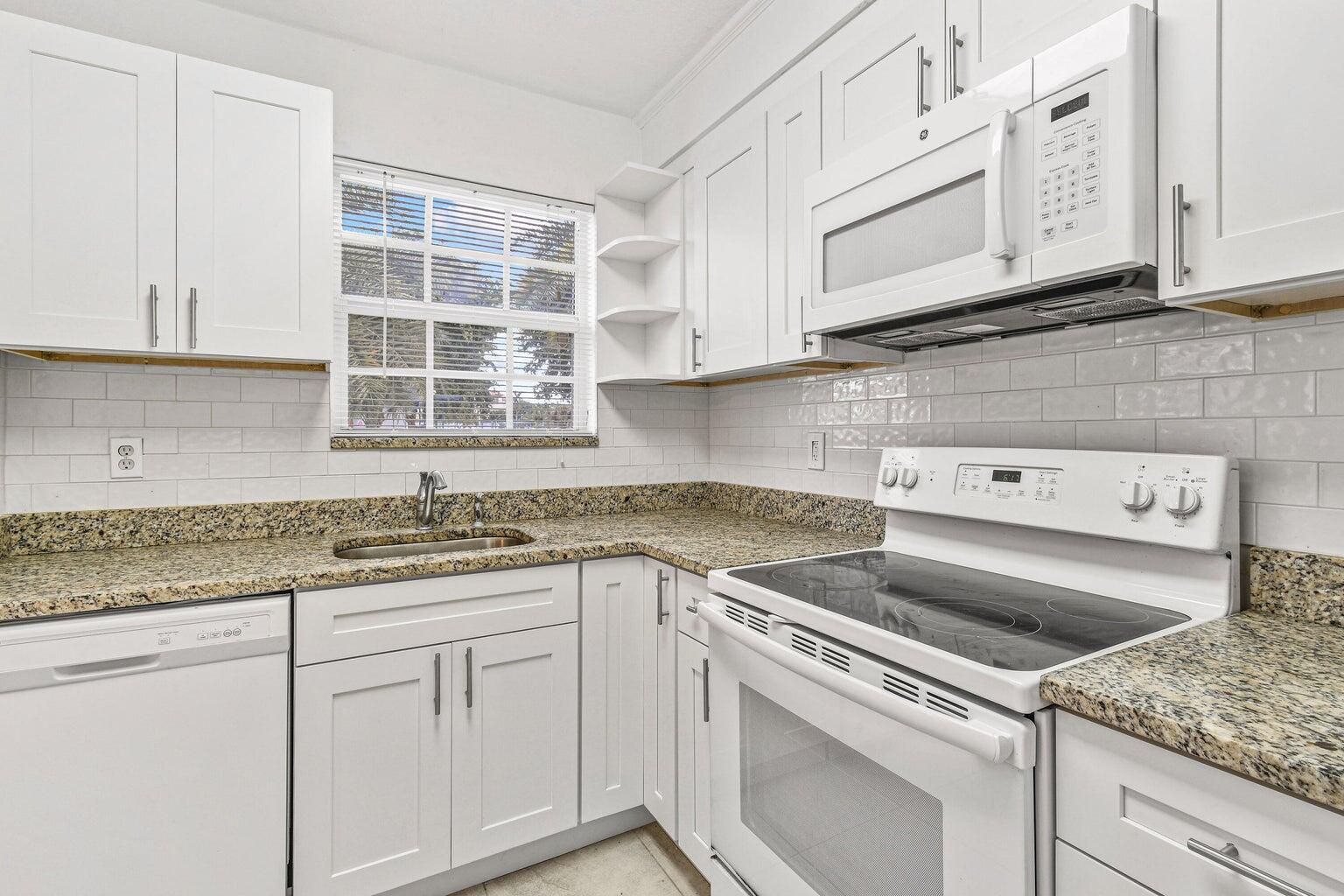 101 Akron Street, Unit 101 Lake Worth Beach, FL 33461 - Photo 5 of 11 a kitchen with granite countertop white cabinets and a sink