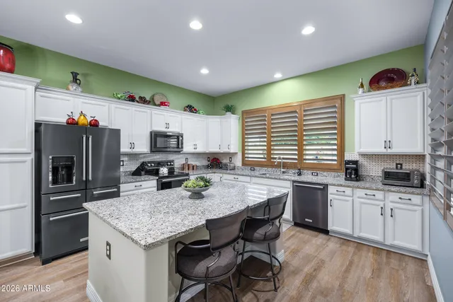 a kitchen with granite countertop a sink stainless steel appliances and white cabinets