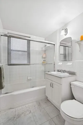 a bathroom with a granite countertop sink a toilet and shower