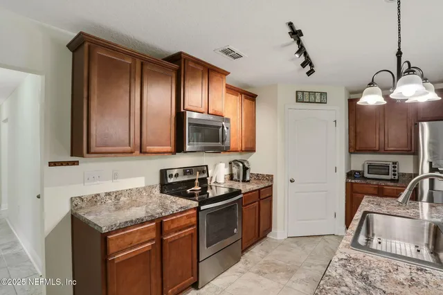 a kitchen with stainless steel appliances granite countertop a dining table chairs refrigerator and sink
