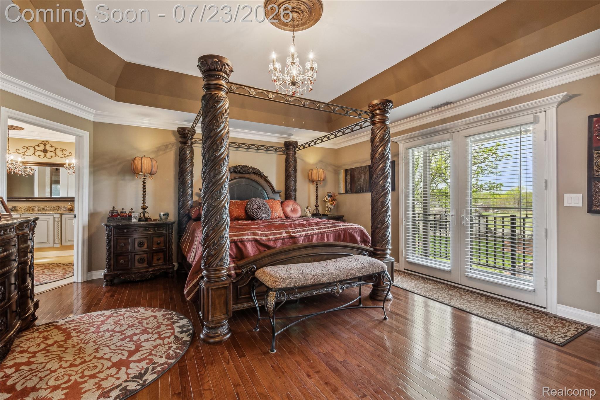5460 Cochrane Road Almont, MI 48003 - Photo 21 of 48 Spacious bedroom featuring wood-finish flooring, a tray ceiling with a decorative chandelier, and double French doors opening to an exterior balcony