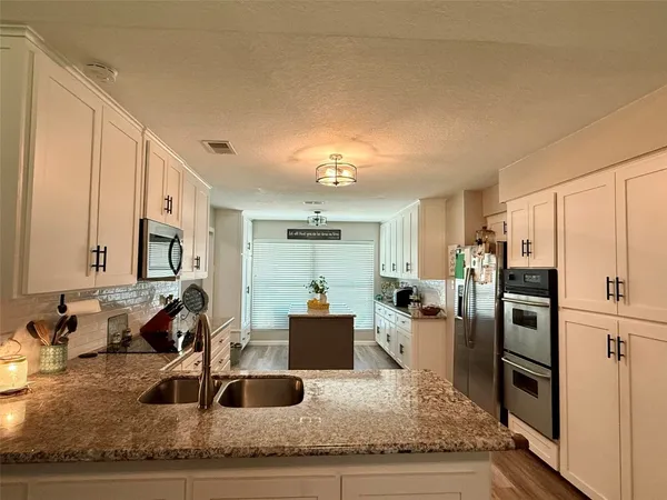 a large kitchen with granite countertop a refrigerator sink and stove