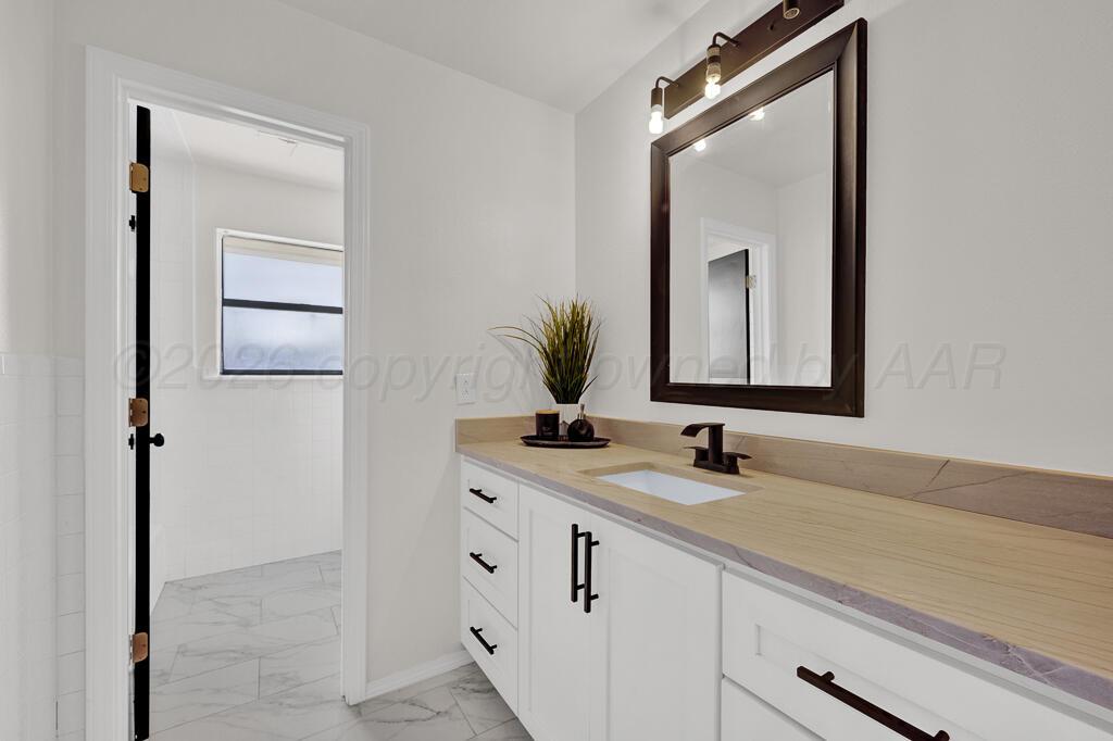 8027 Simpson Drive Amarillo, TX 79121 - Photo 19 of 32 a bathroom with a double vanity sink and a mirror
