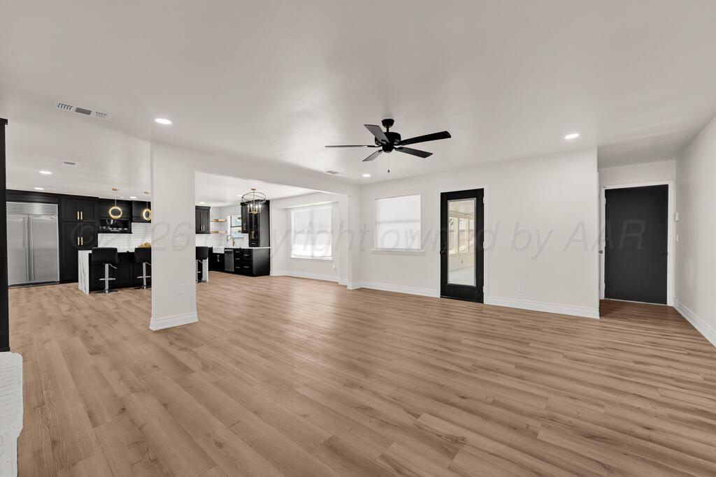 8027 Simpson Drive Amarillo, TX 79121 - Photo 7 of 32 a view of an empty room with wooden floor and a kitchen