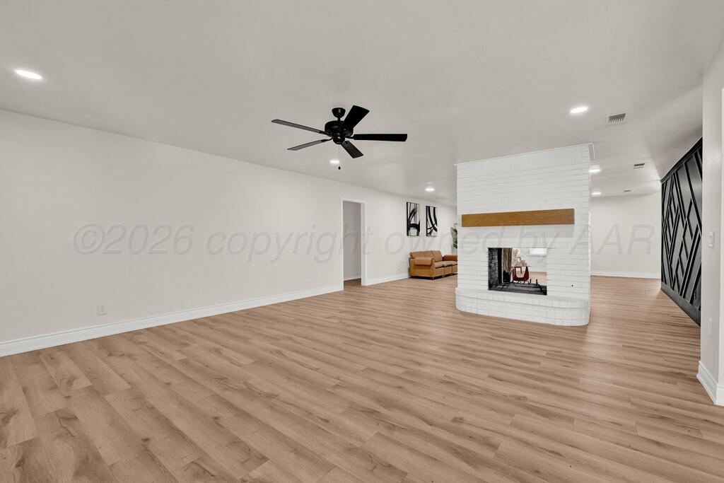 8027 Simpson Drive Amarillo, TX 79121 - Photo 8 of 32 a view of a livingroom with a ceiling fan a fireplace and wooden floor