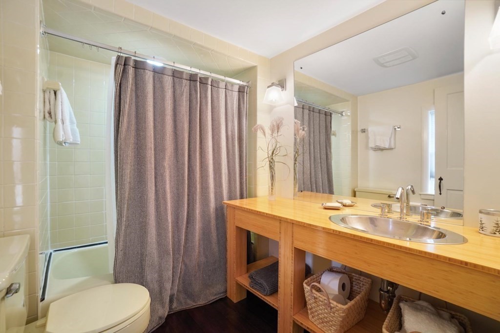 1219 High Street Westwood, MA 02090 - Photo 25 of 30 a bathroom with a sink a toilet a mirror and shower curtain